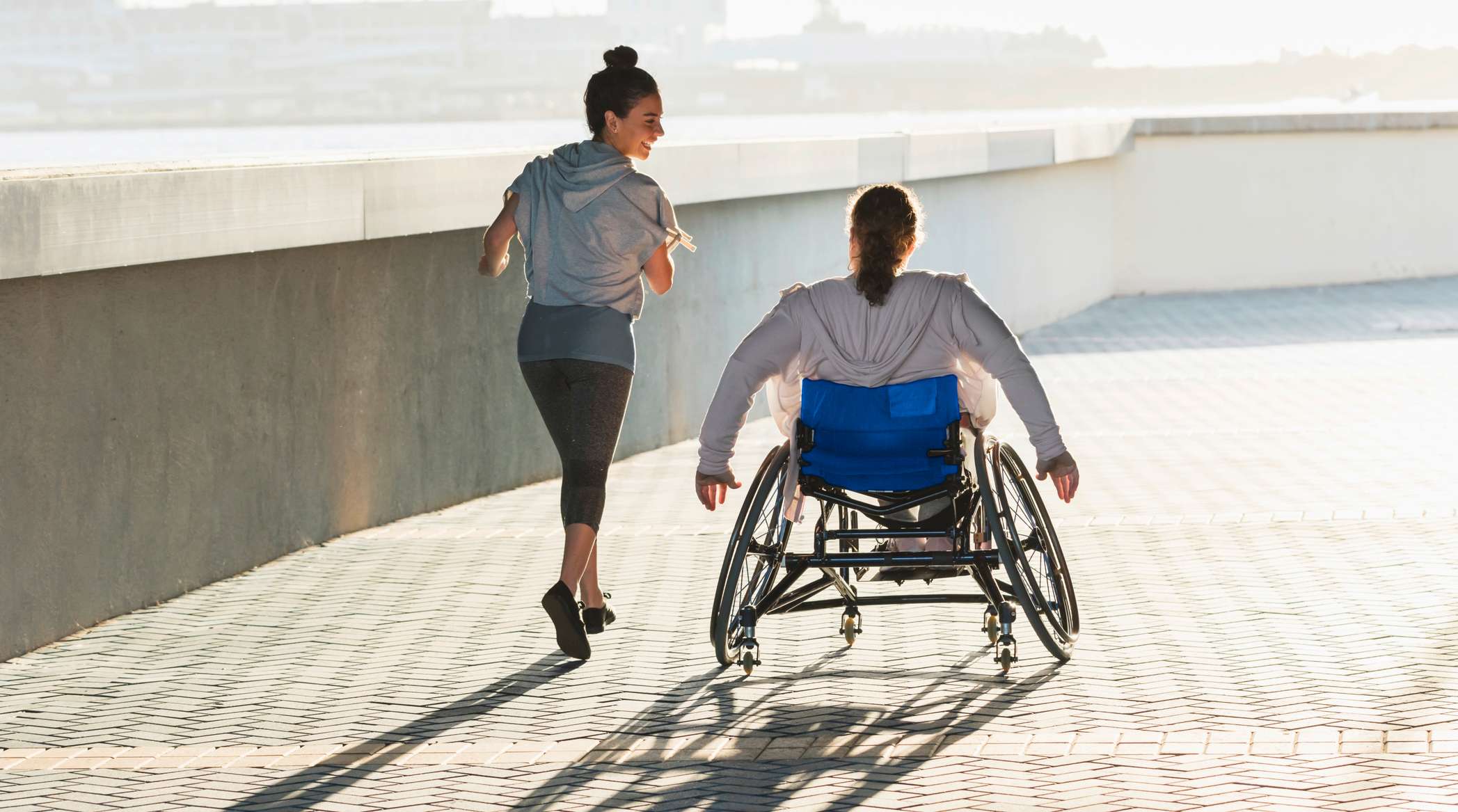 Joggerin begleitet eine Rollstuhlfahrerin