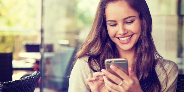 junge Frau schaut auf ihr Handy und lächelt - Das Bild ist urheberrechtlich geschützt. Eine Nutzung ohne vorherige Einwilligung ist nicht gestattet. junge Frau schaut auf ihr Handy und lächelt