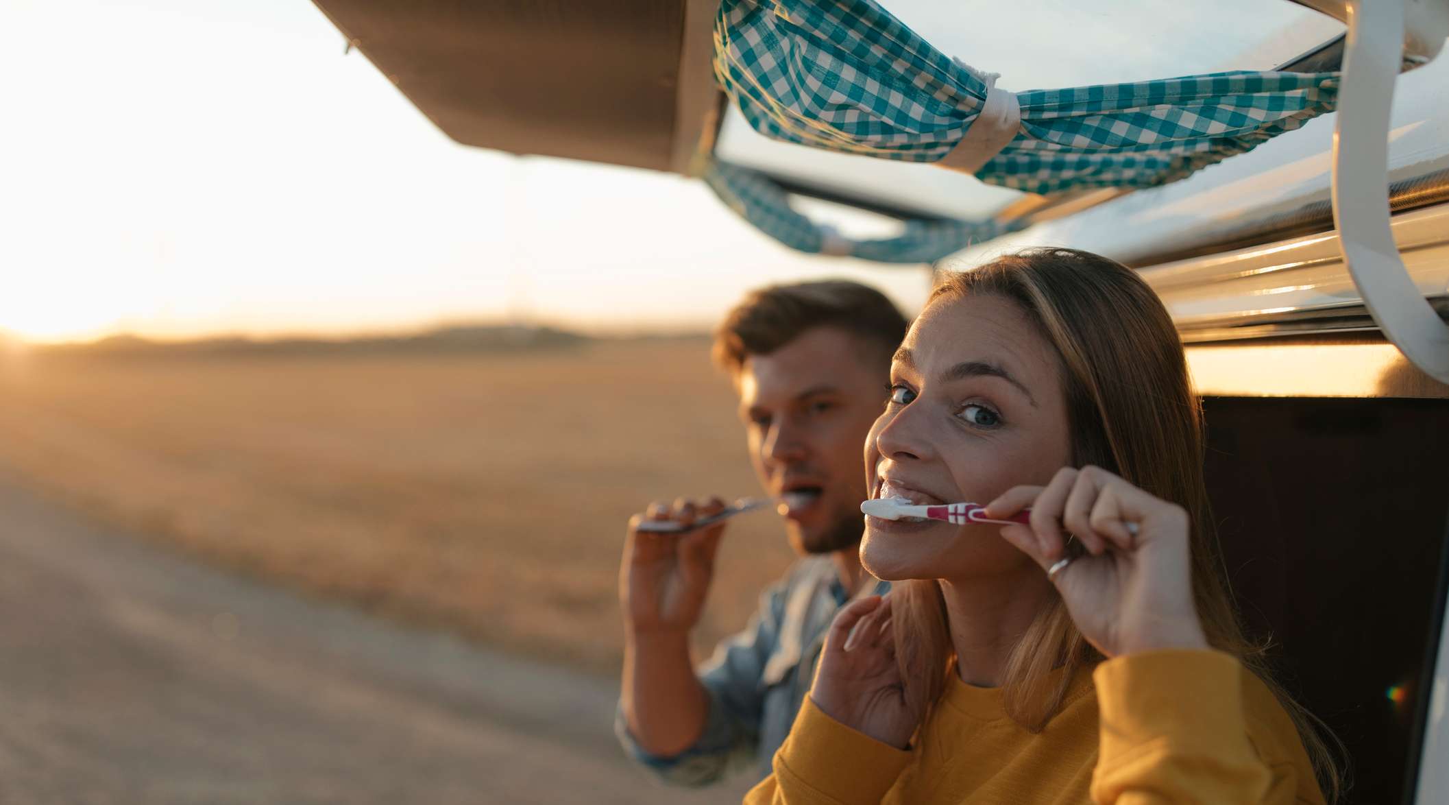Zwei junge Menschen putzen sich die Zähne im Freien