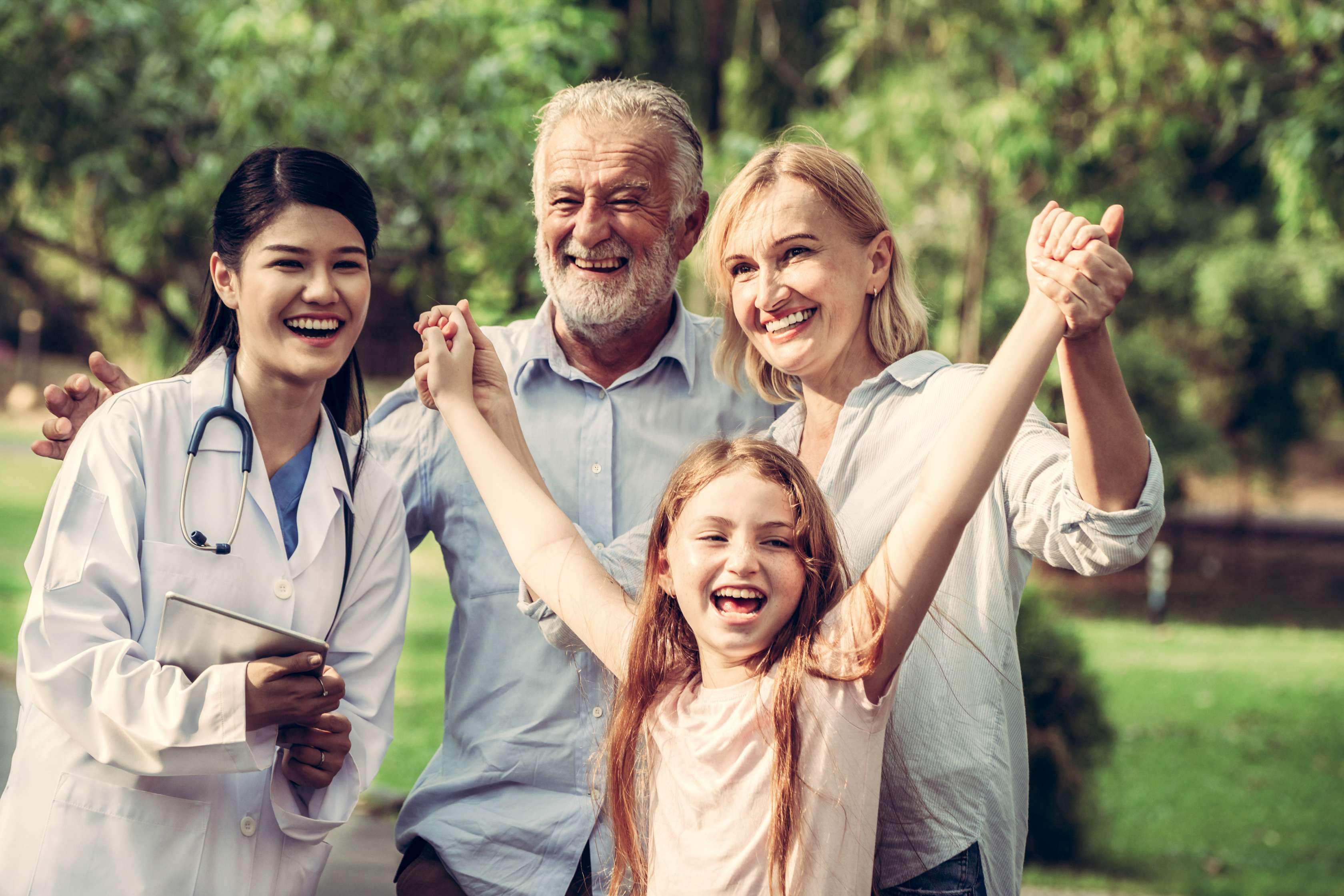 Familie mit Kind steht freudig im Garten mit einer Ärztin