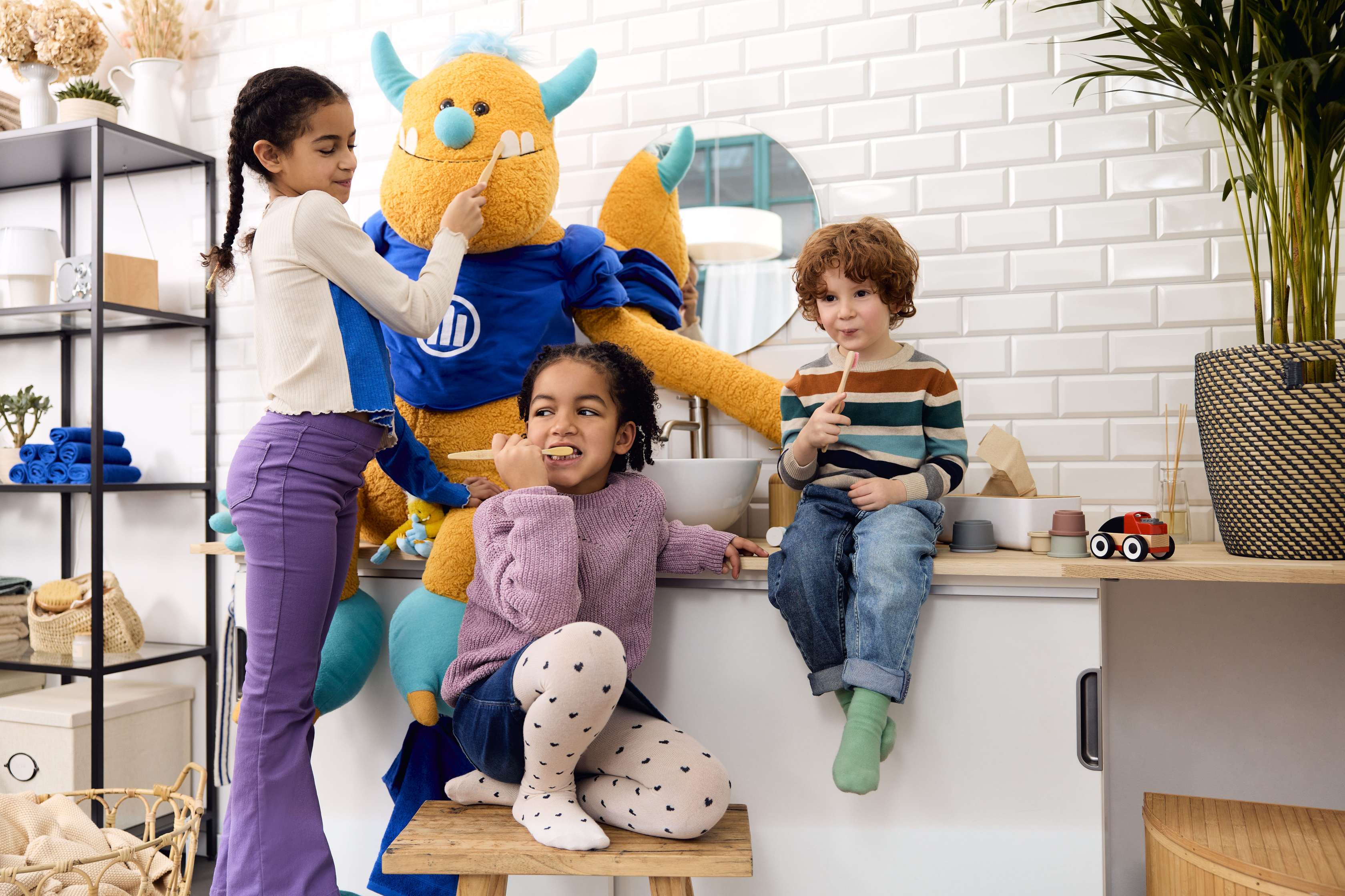 Kinder knuddeln ein Kuschelmonster und putzen Zähne