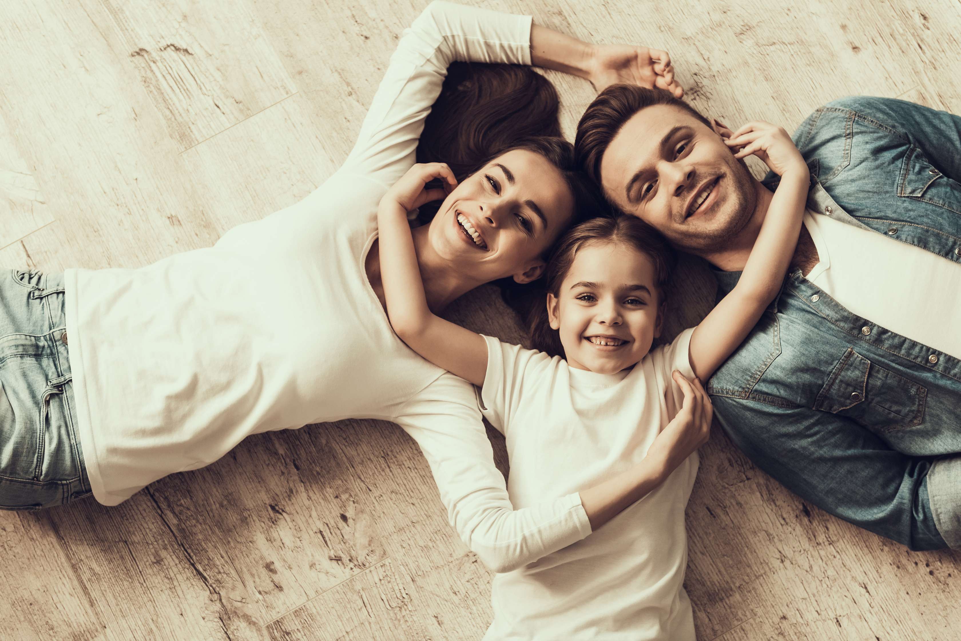Junge Familie liegt umarmend auf dem Boden