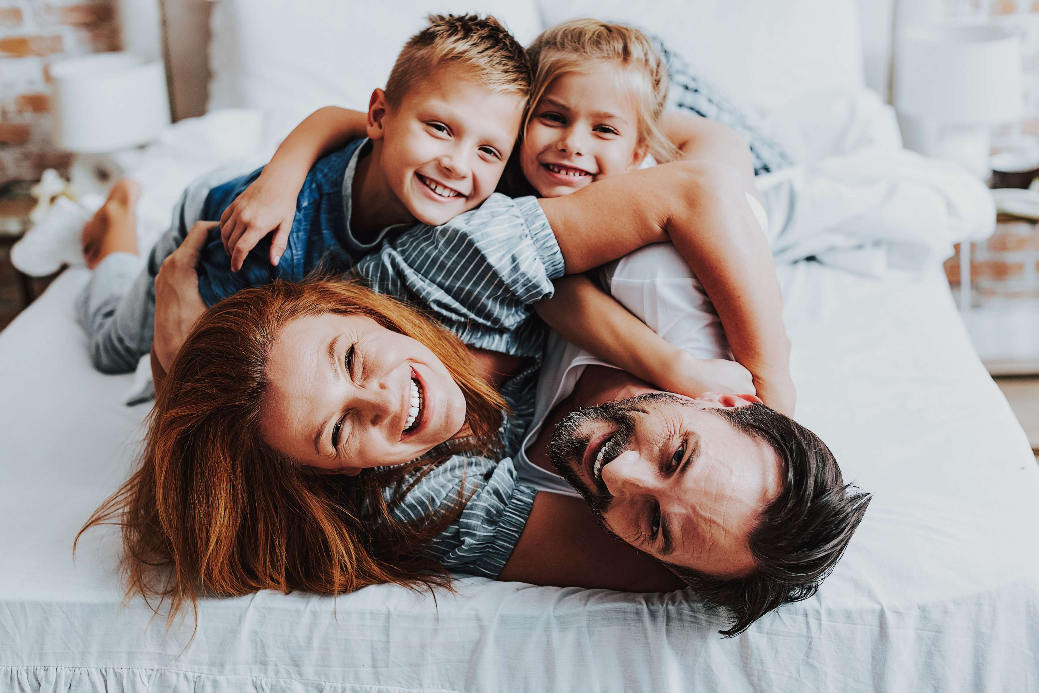 Familie mit zwei Kindern toben im Bett