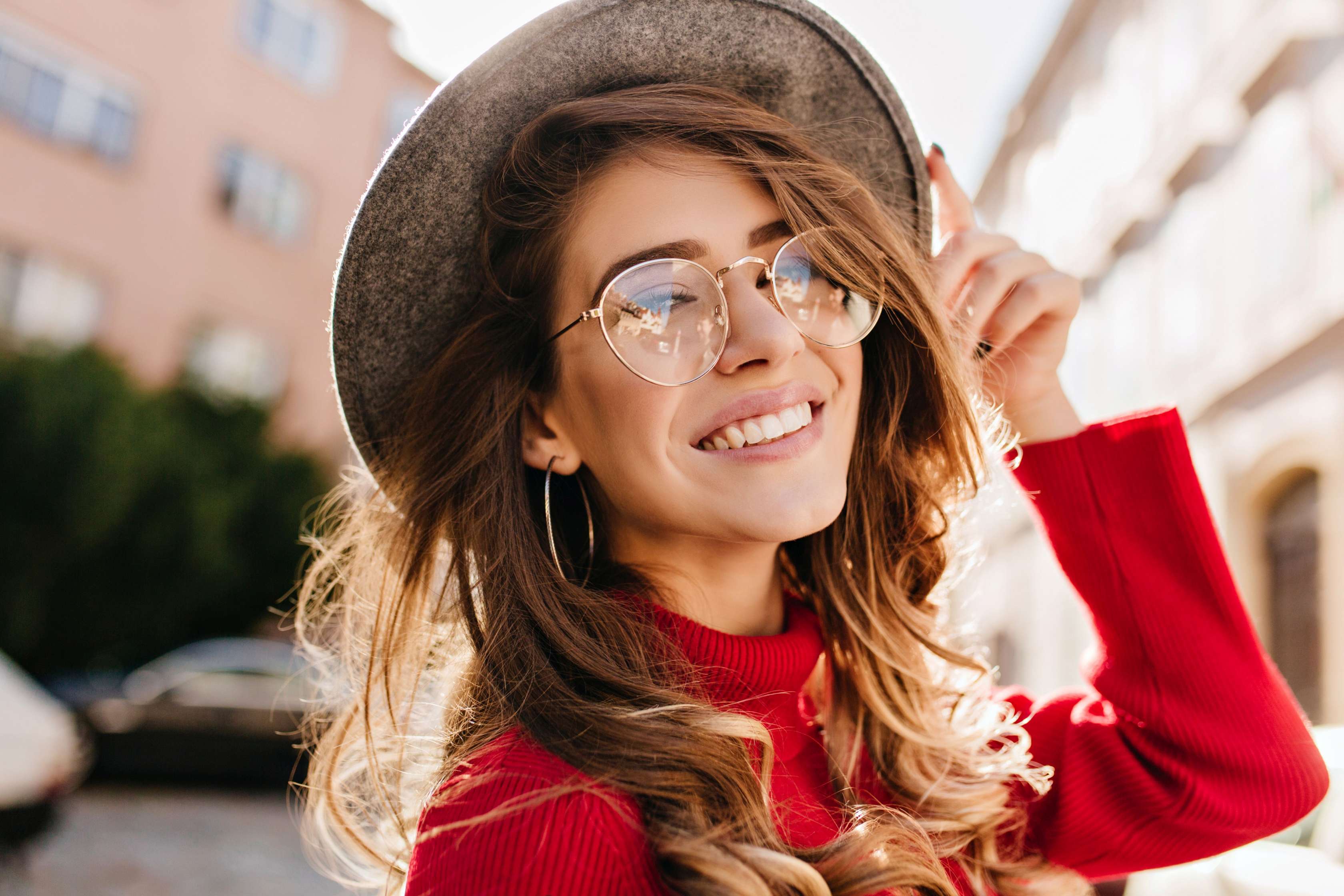 junge Frau mit Brille und Hut lächelt