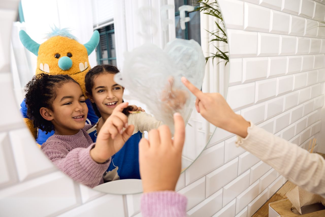 Kinder malen mit Zahnpasta an Spiegel