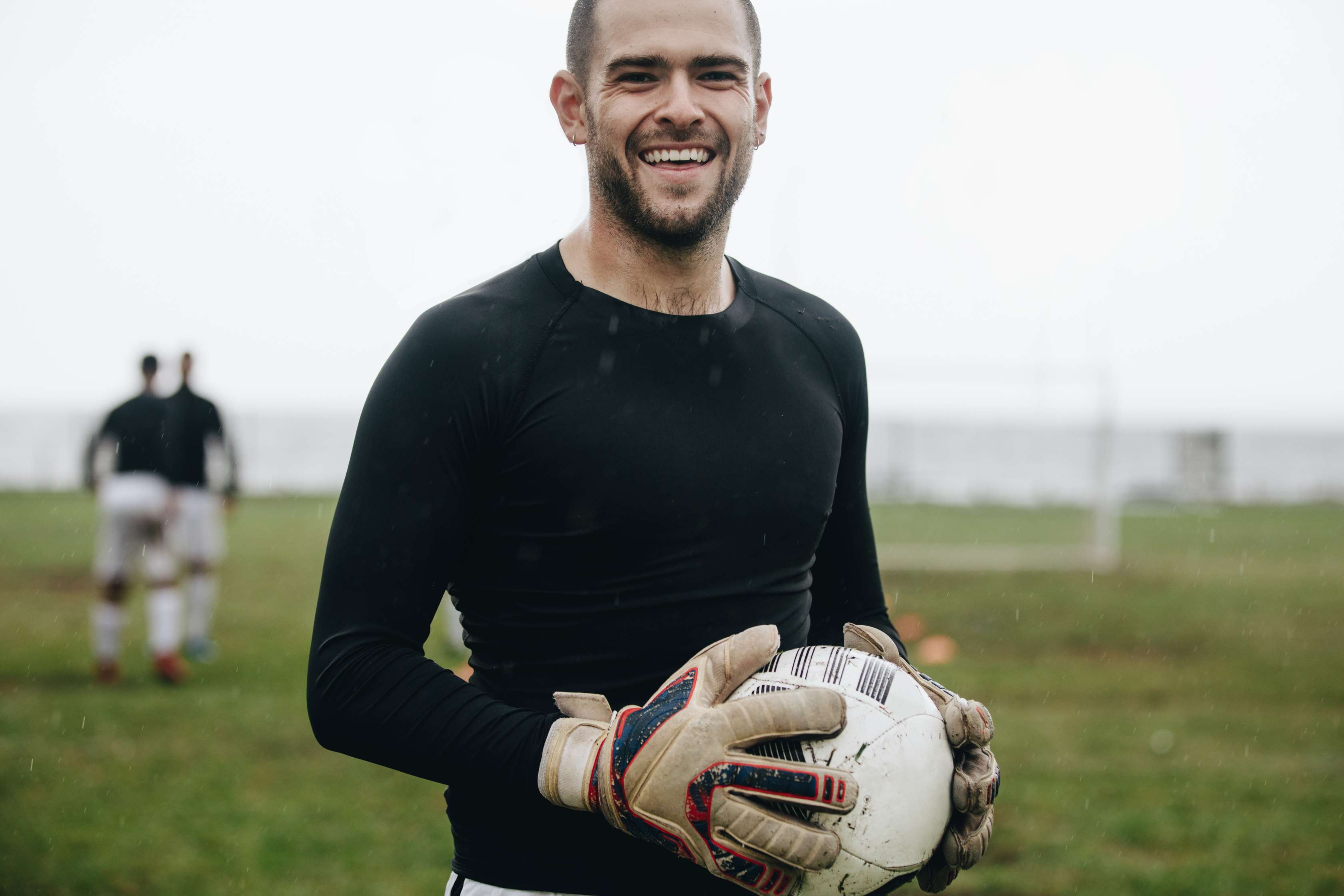 junger Mann hält einen Fußball in den Händen und lacht