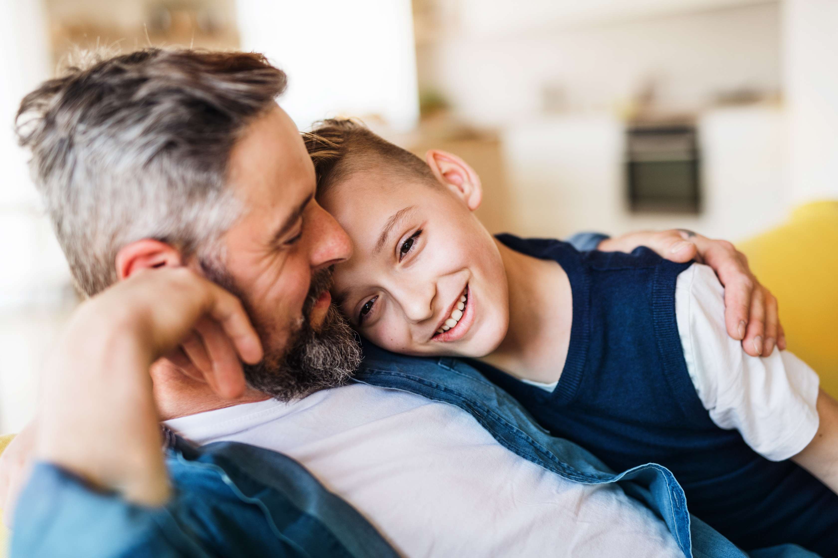 Vater umarmt Sohn auf Couch