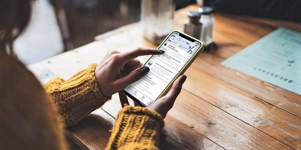 Frau am Tisch mit Handy in der Hand Frau am Tisch mit Handy in der Hand