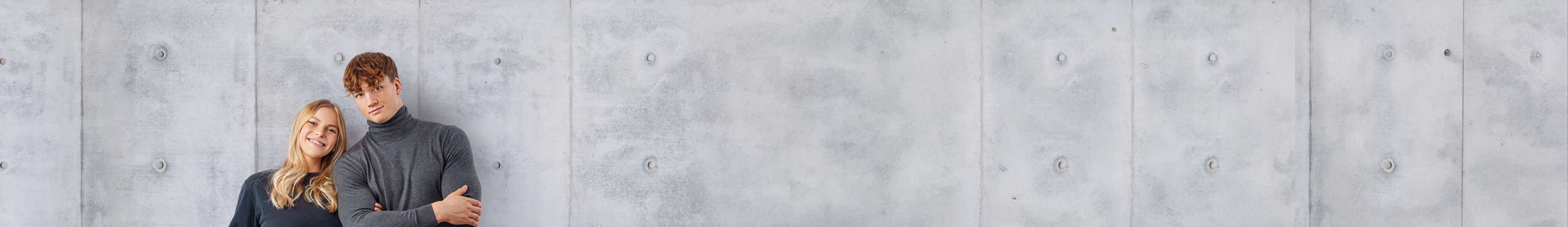 Zei Jugendliche Stehen an einer Wand und lächeln in die Kamera