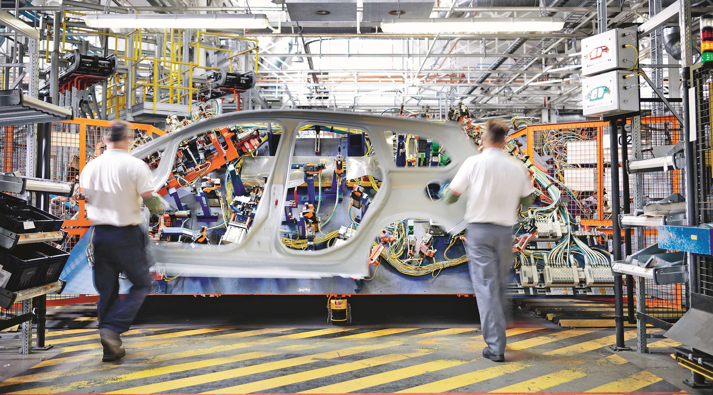 Zwei Arbeiter tragen einen Pkw Rahmen