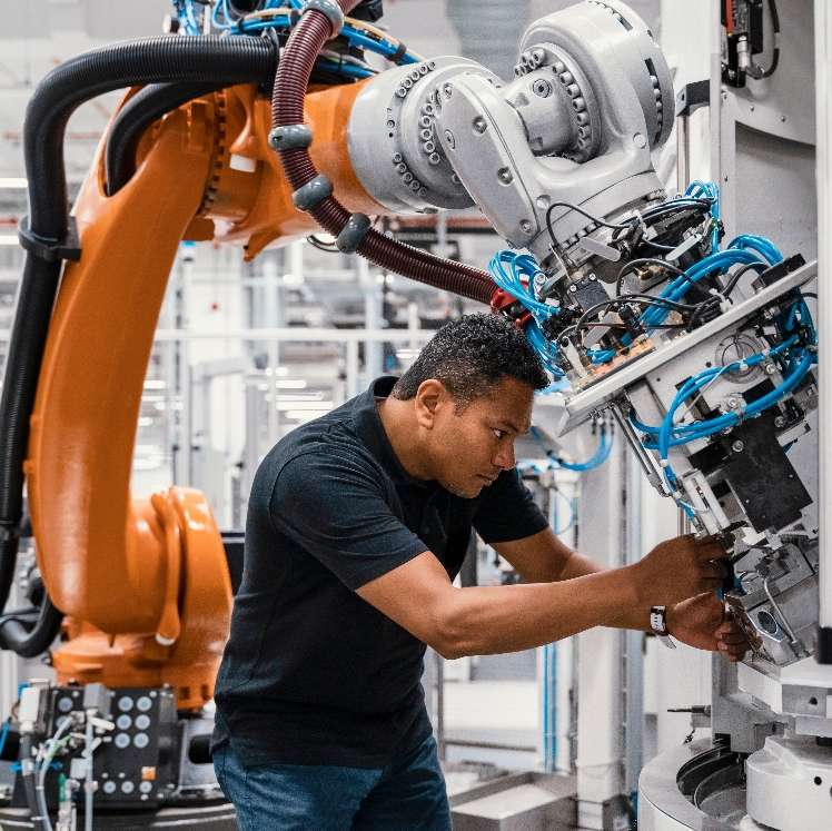 Arbeiter hantiert an einem Roboterarm