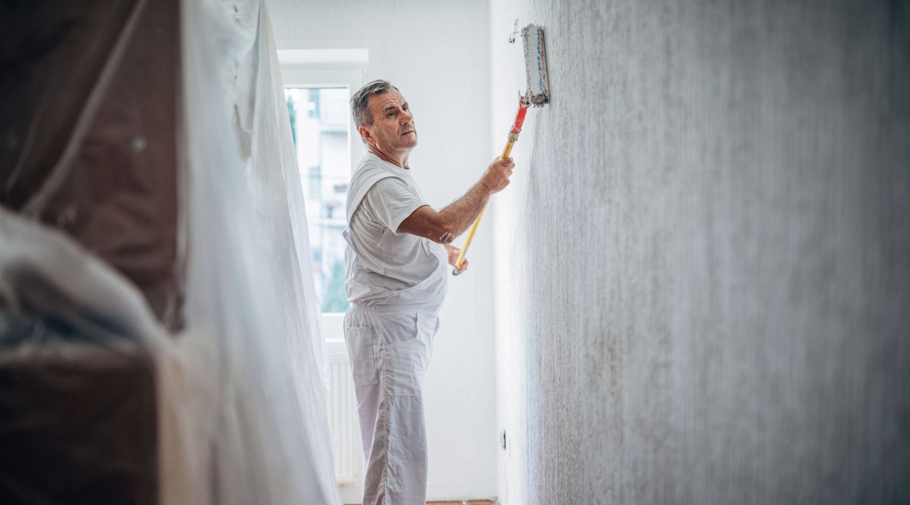 Maler mit Farbroller malert eine Wand