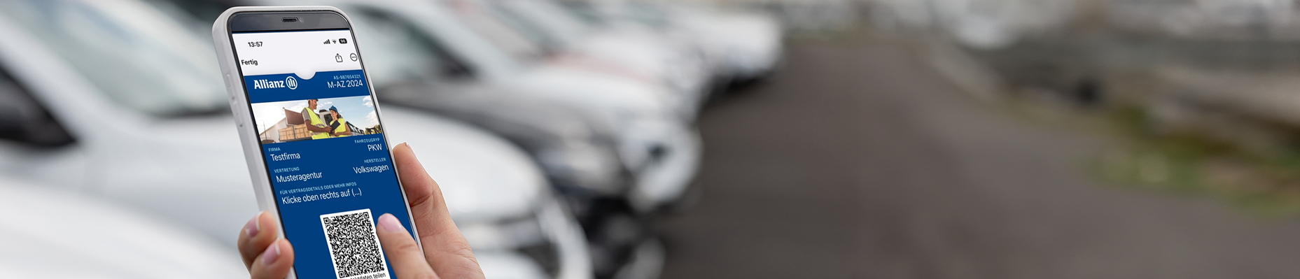 Handy mit QR-Code und im Hintergrund mehrere Fahrzeuge