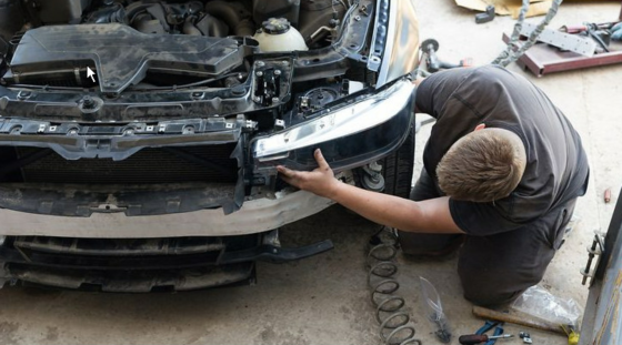 Ein Automechatroniker installiert einen Scheinwerfer