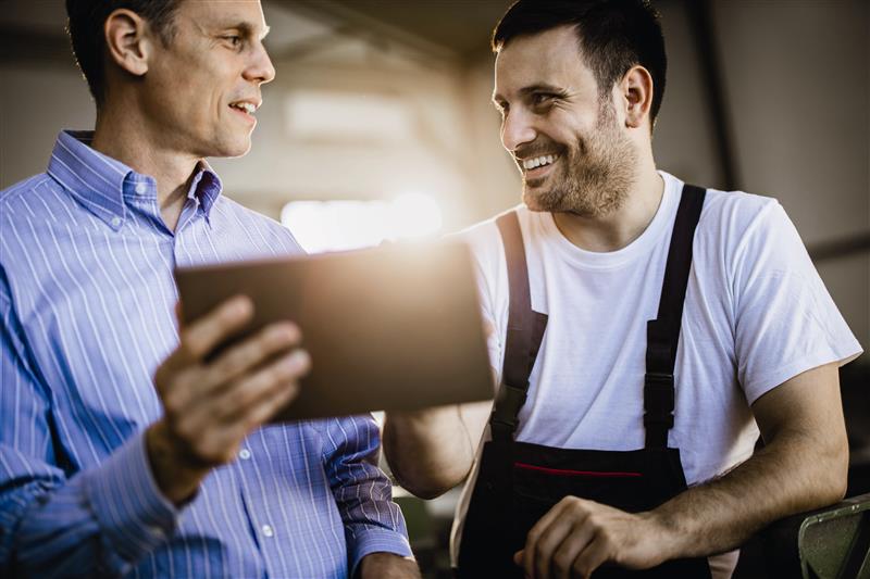 Arbeiter mit Latzhose lehnt an PKW