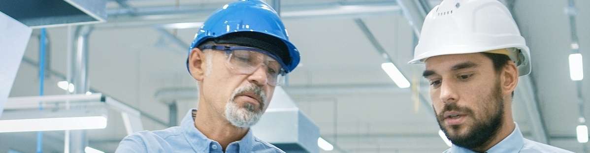 2 Personen mit Schutzhelm blicken auf Notebook