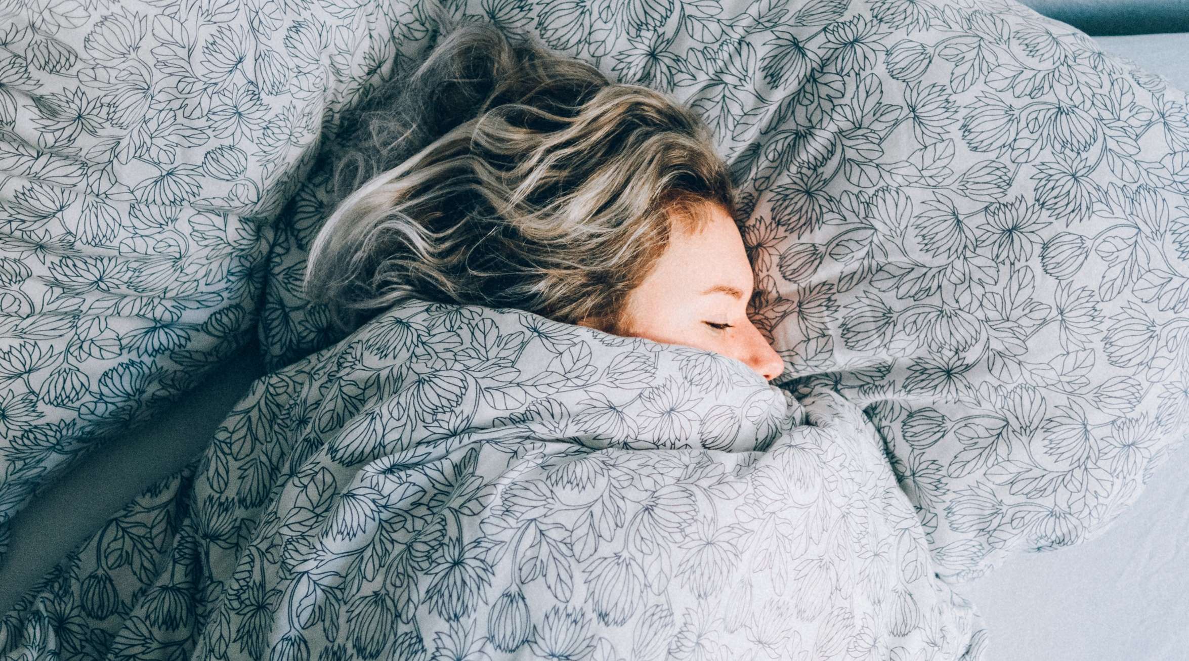 Frau liegt zugedeckt im Bett