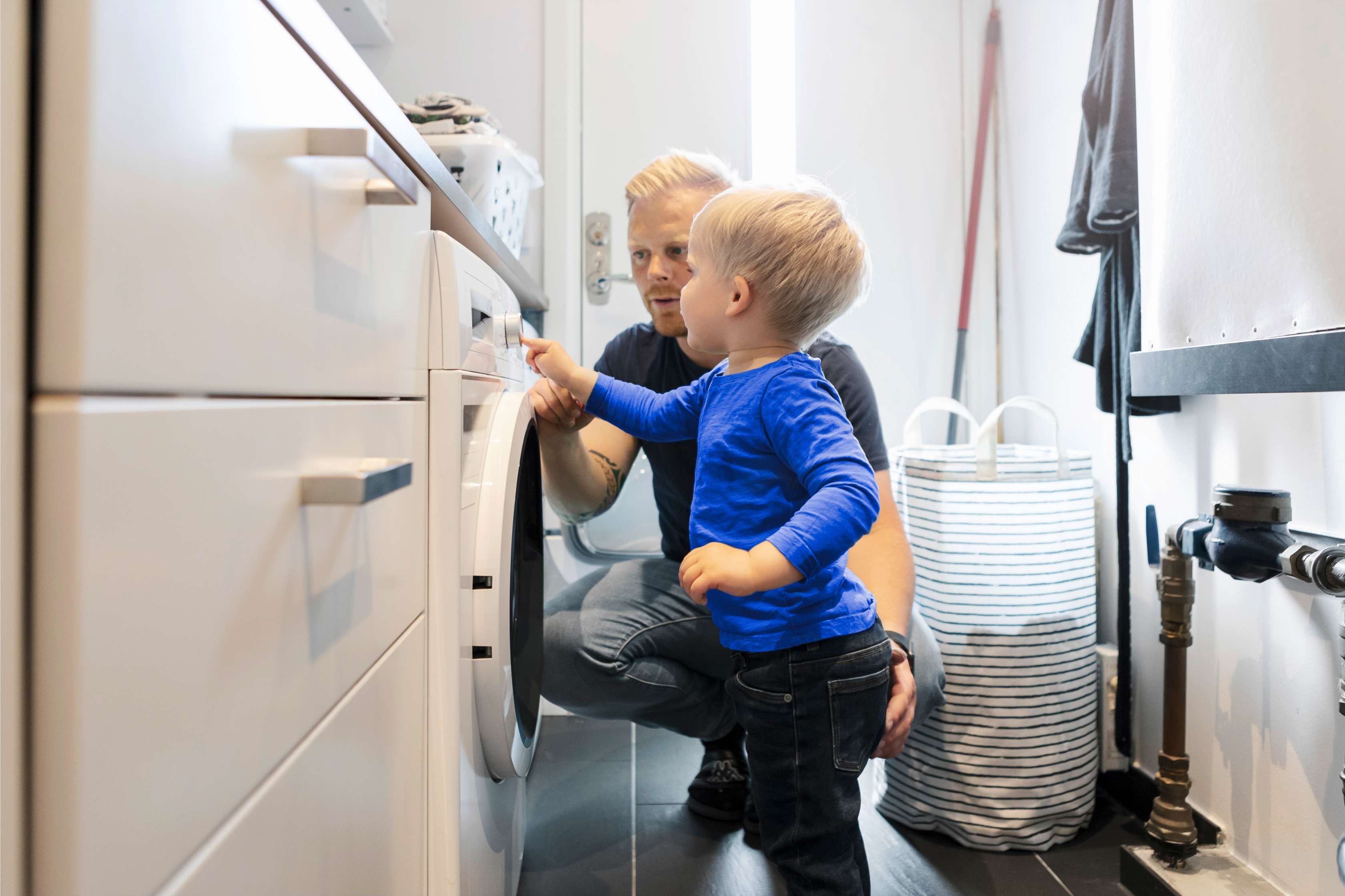 Kleines Kind drückt Knopf bei Waschmaschine