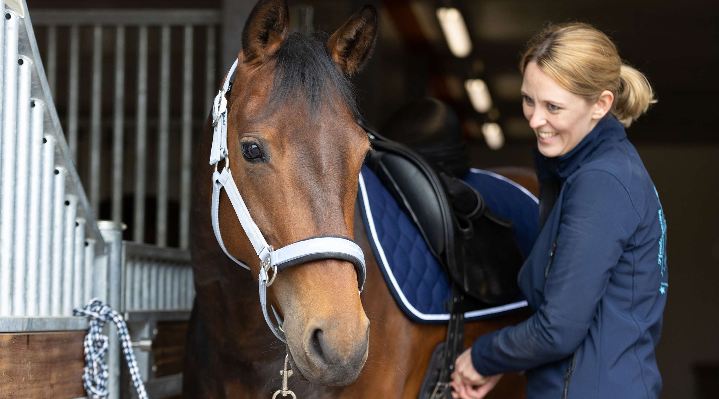 Reiterin sattelt ein Pferd