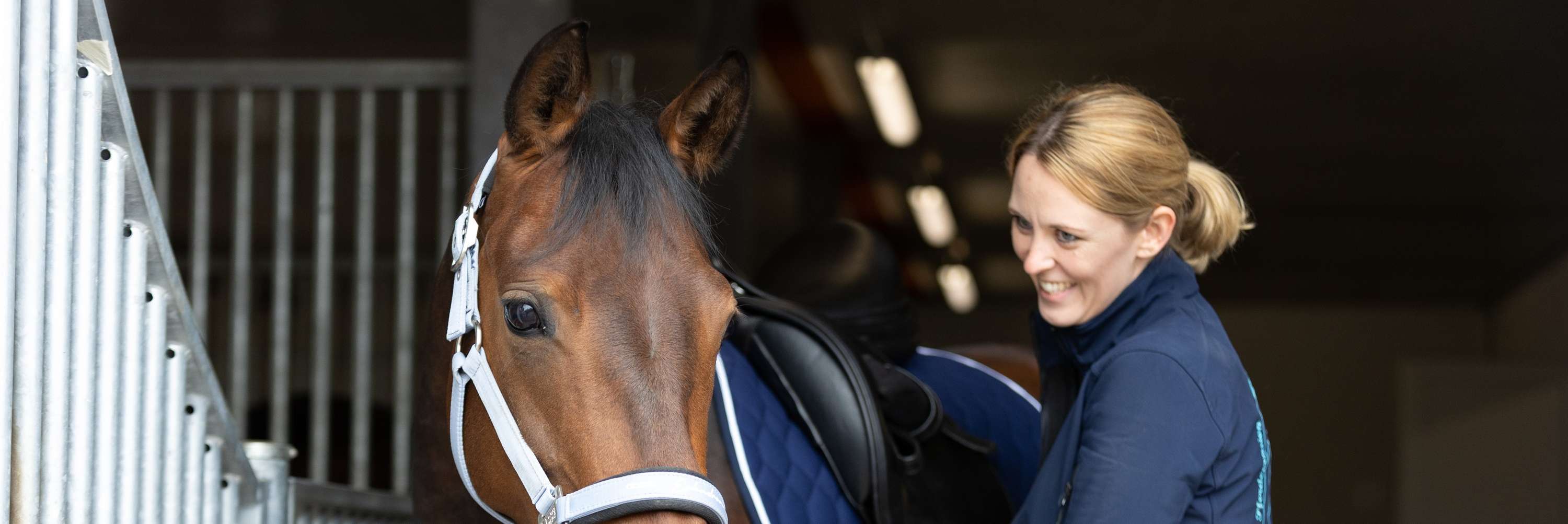 Reiterin sattelt ein Pferd