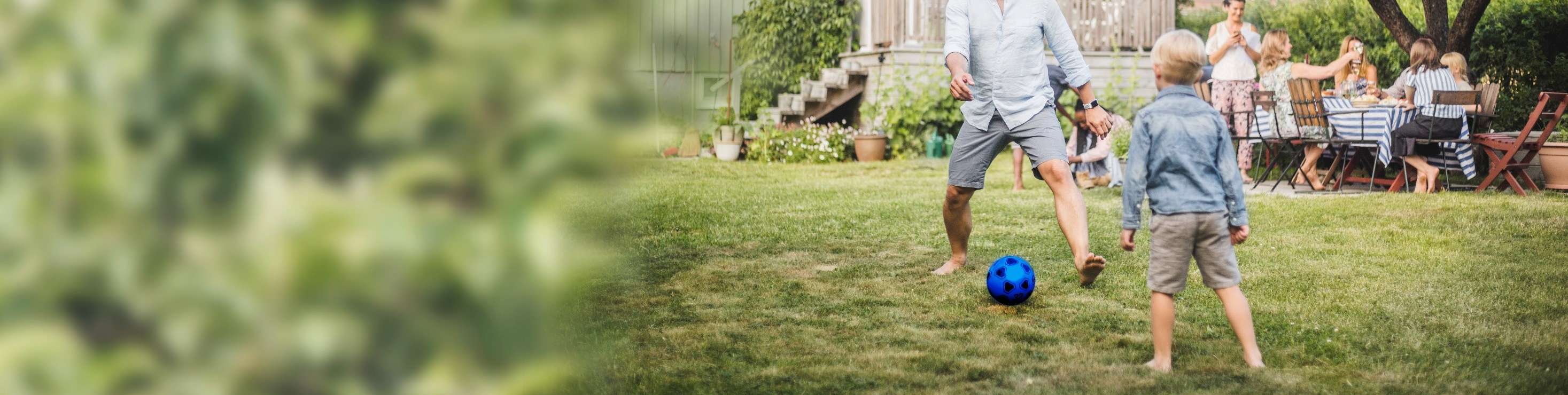 Mann und Kind spielen Fußball im Garten