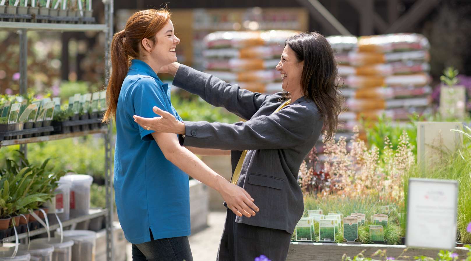 Zwei Angestellte umarmen sich in einer Gärtnerei