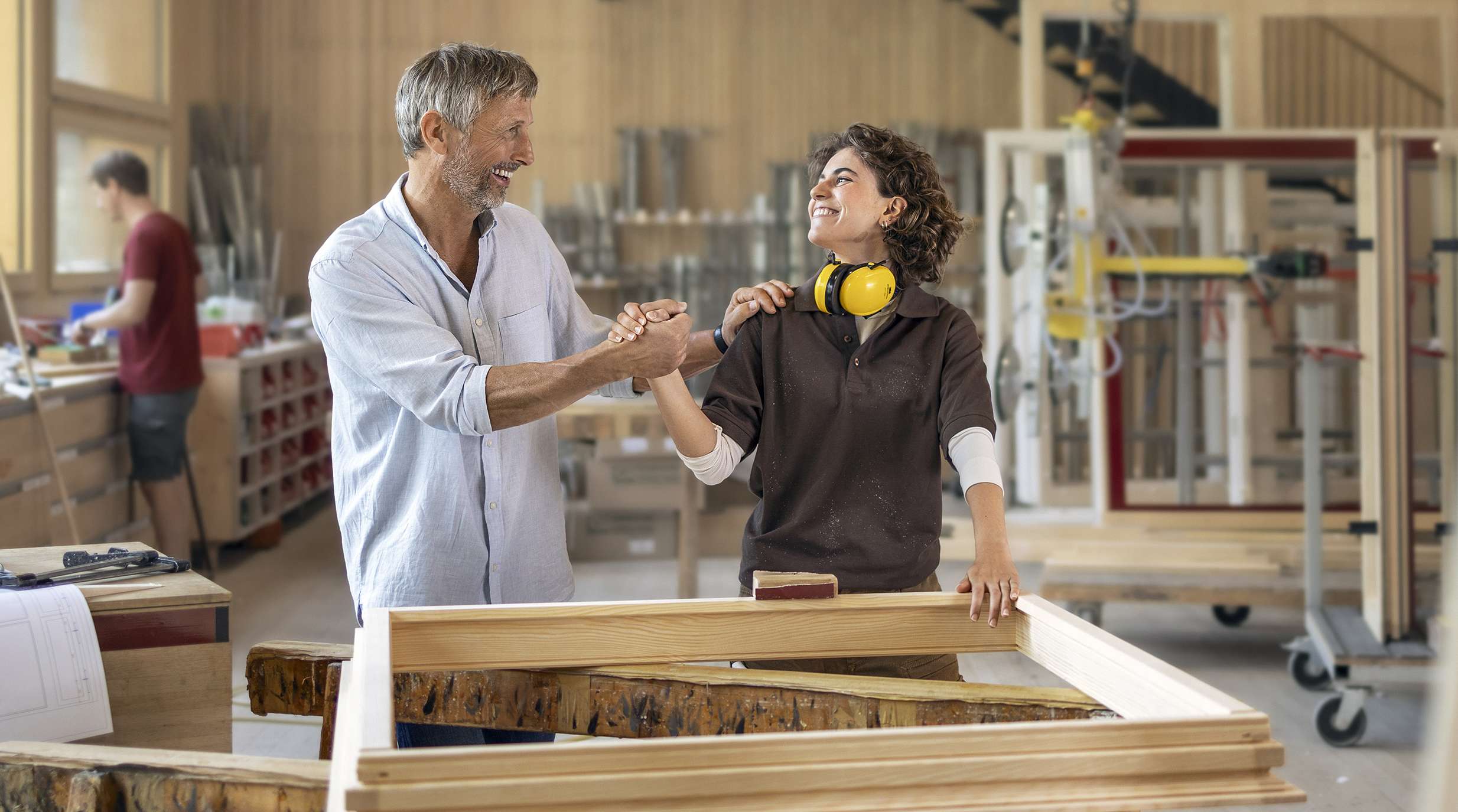 Zwei Personen geben sich in einer Werkstatt die Hand