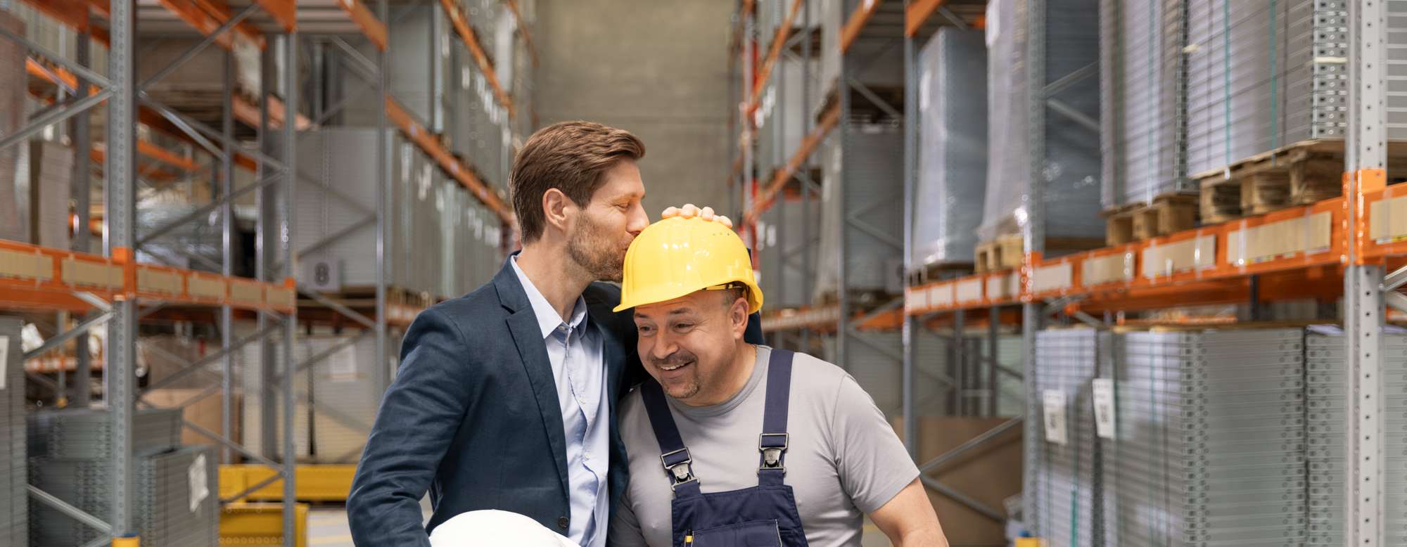 Arbeitgeber küsst Mitarbeiter auf Schutzhelm